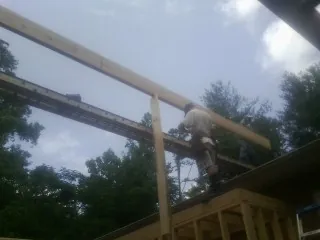 Carpenter setting a ridge beam over a new addition frame — Ice Dam Removal by Roofing Brothers in Braman