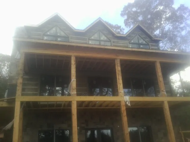 Dormers and porch framing on a large log home under construction — Roof Coating work by our crew in Braman