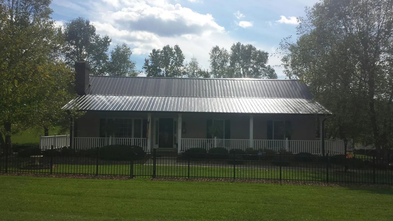 Gray metal roof on a brick ranch with a full width front porch — Gutter Guard Installation work by our crew in Braman
